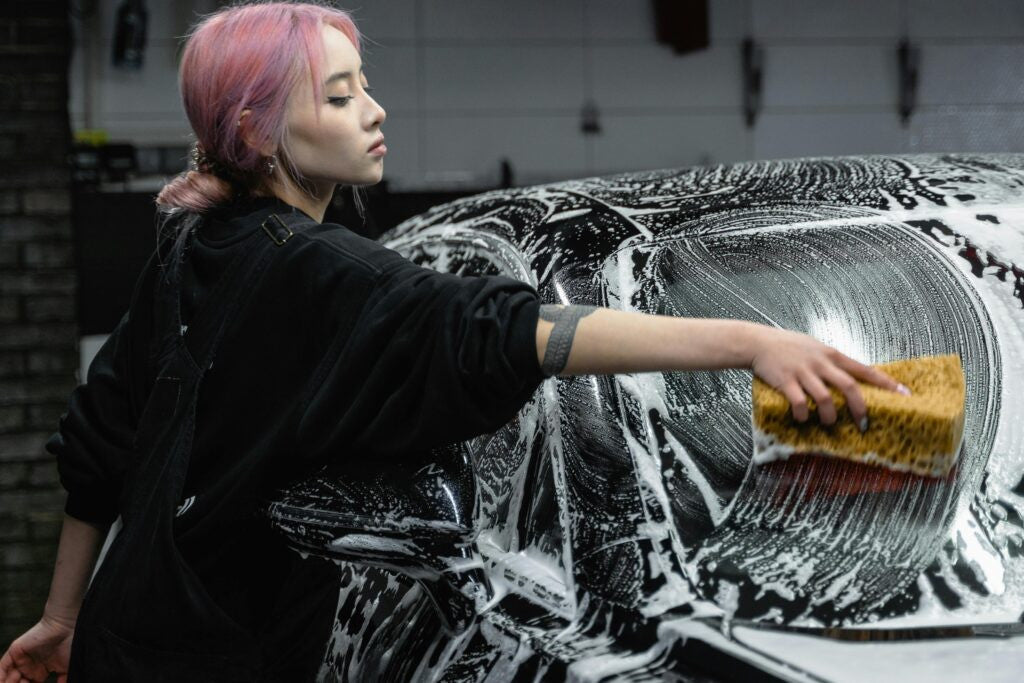 Woman washes a car window